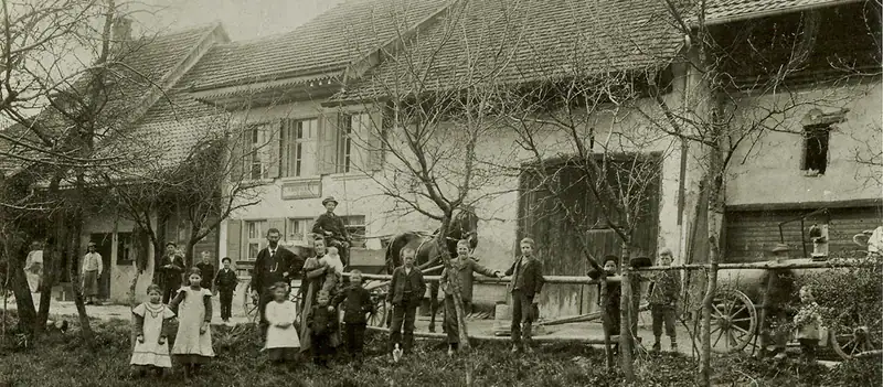 Historische Aufnahme des Bauernhauses mit Familie, Kindern und einem Wagen davor