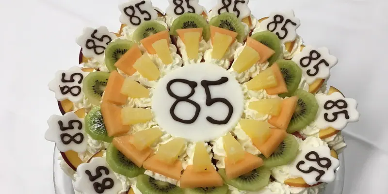 Geburtstagstorte mit der Zahl 85, verziert mit Kiwi, Ananas und Melone