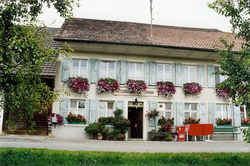 Das Haus um 1950 mit heller Fassade, hellblauen Fensterläden und roten Blumenkästen