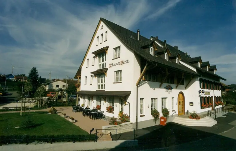 Das neu gebaute Restaurant um 2000 mit weisser Fassade, dunklem Dach und gepflasterter Terrasse