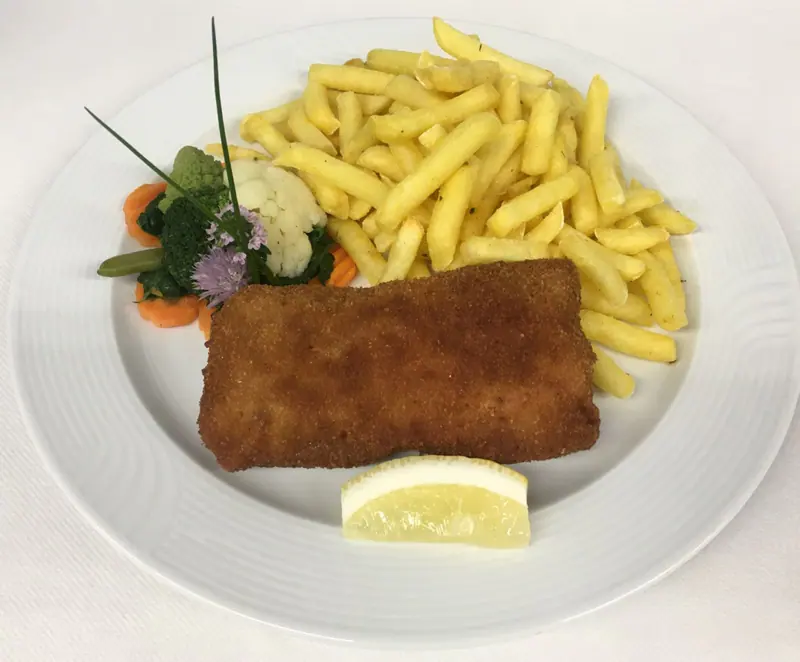 Cordon bleu mit Pommes frites, Gemüse und Zitronenschnitz auf einem weissen Teller