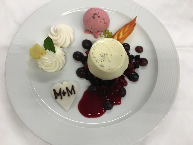 Dessertteller mit Creme, Beeren, Glace, Rahmtupfen und einem Zuckerherz
