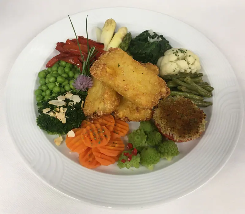 Rösti Pick mit vielfarbiger Gemüsegarnitur auf einem weissen Teller