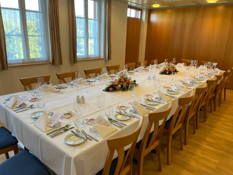 Saal 2 mit langer Blocktafel, Blumenschmuck und hellen Fenstern