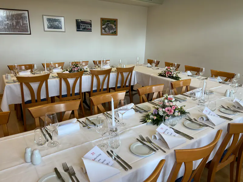 Saal 2 in U-Form gedeckt, mit Blumengestecken, Kerzen und gefalteten Servietten