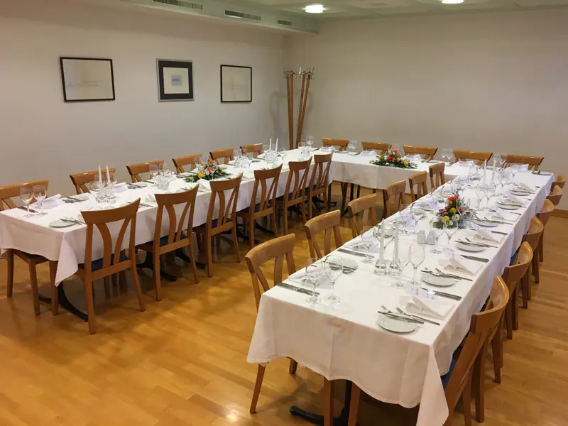 Saal 2 in U-Form: gedeckte Tische im hellen Raum, an der Wand gerahmte Bilder